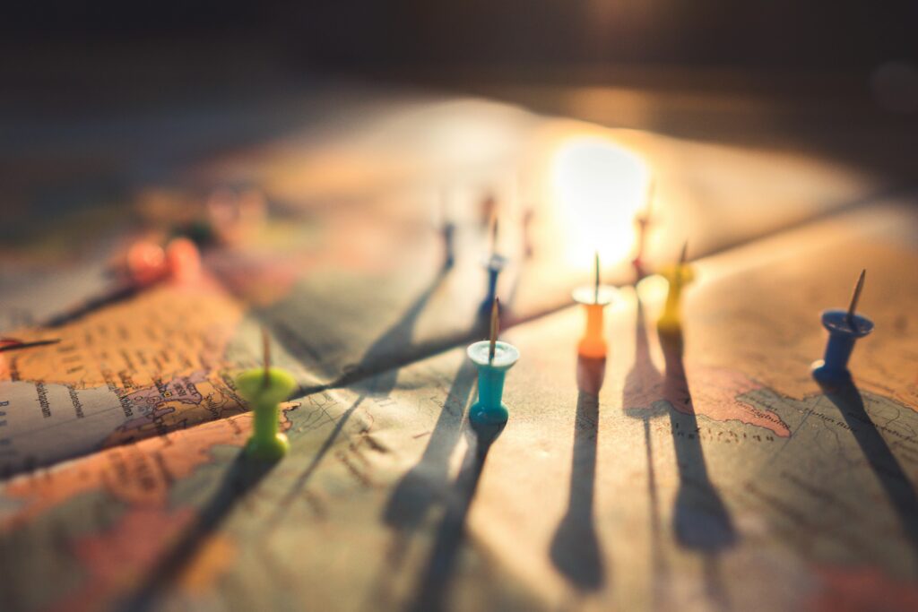 Punaises d'épinglage tournées vers le haut et posées sur une carte routière. L'image est prise à contre jour. Elle illustre la carte des partenaires de l'Ecole Jardin Foret