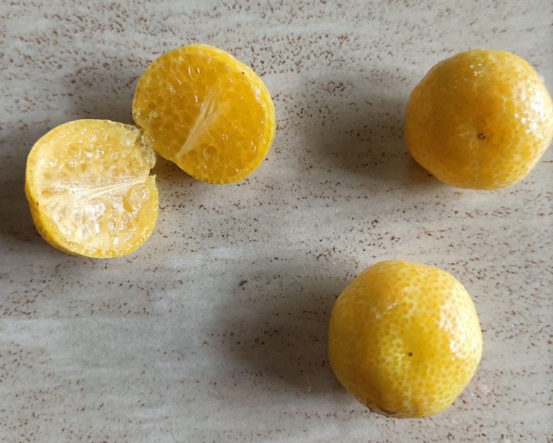 Photo de 3 érémorange ou orange à caviar coupées en 2. La texture intérieure du fruit à l'air composée d'un multitude de grains de taille moyenne.
