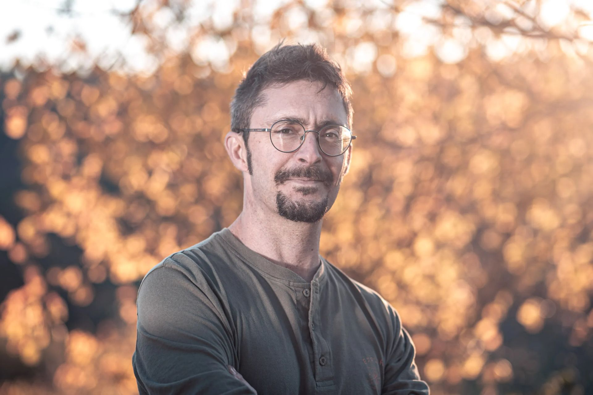 Portrait d'un homme blanc châtain d'une quarantaine d'années, portant des lunettes. Le fond est flou et évoque des arbres dans une lumière d'automne. Il s'agit d'un portrait de Mathieu Foudral de Prise de Terre